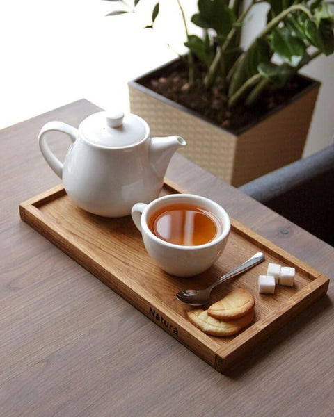 A serving tray with tea and cookies sitting on a matte finished wood table in a restaurant.