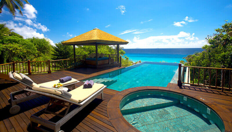 A luxury tropical resort hardwood deck and infinity pool.