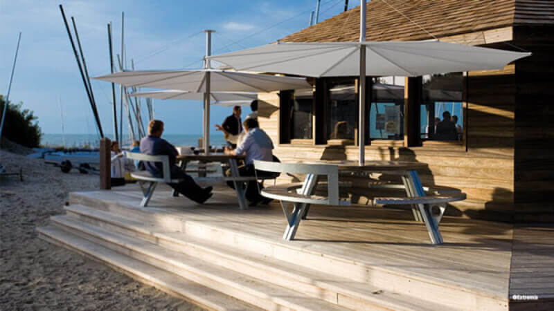 Round tables sitting on a patio by the beach.