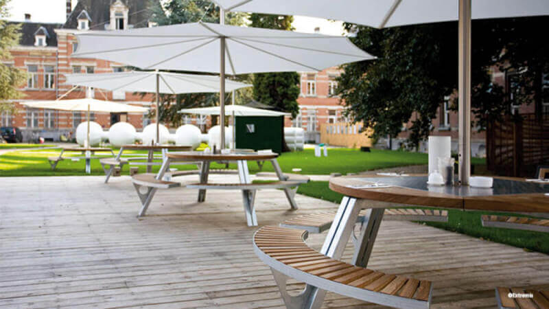 A couple round patio tables with umbrellas sitting on a wood patio.