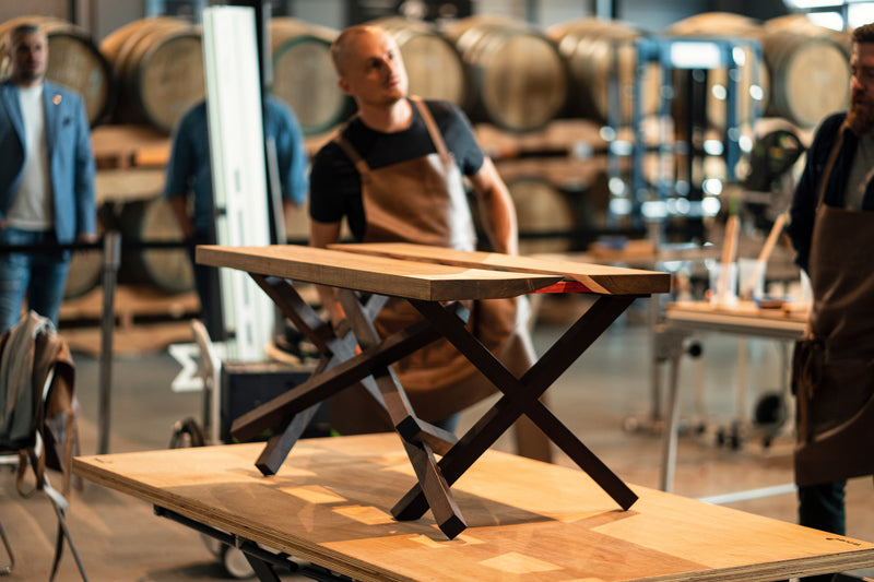 A custom wood table with geometric legs sitting on a workbench
