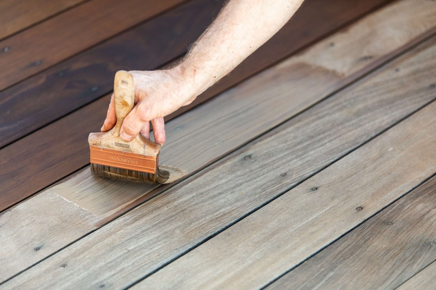 Person applying DuroGrit wood finish to a wooden surface using a brush
