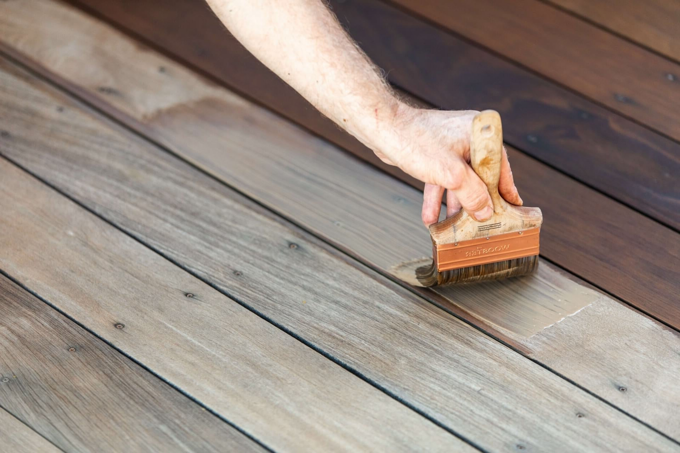 Applying deck stain and finish to deck boards using a paint brush