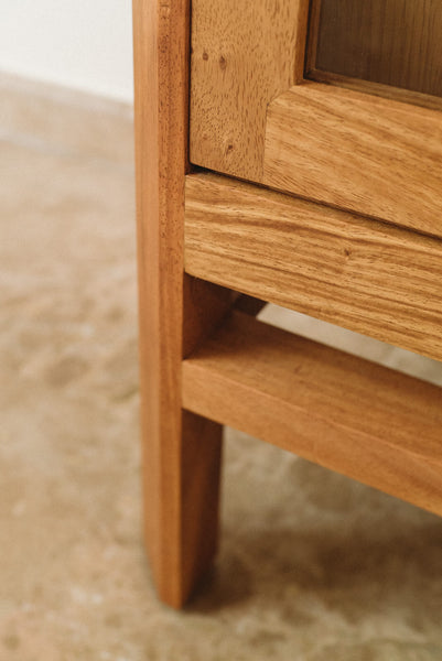 A detail shot of a display cabinet made from Angsana wood. This is the lower right-hand corner of the piece showing a support and a portion of the door. 