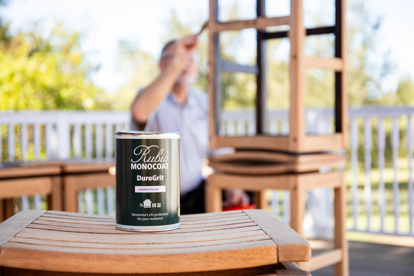 DuroGrit can sitting on stool with professional contractor applying wood stain in the background