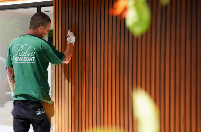 Contractor applying a Rubio Monocoat's durable wood stain and finish on exterior slat wall siding