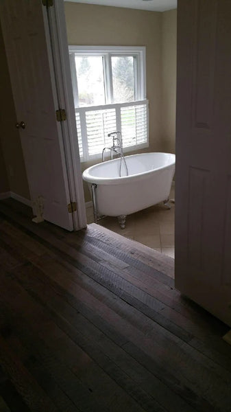 Reclaimed barnwood leading into a bathroom. You can see a clawfoot bathtub through the doorway.