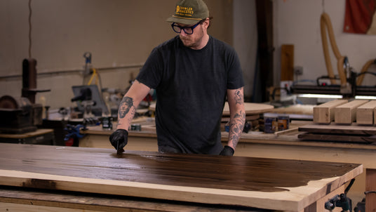 Professional furniture maker applying new Oil Plus 2C wood stain color to a table top
