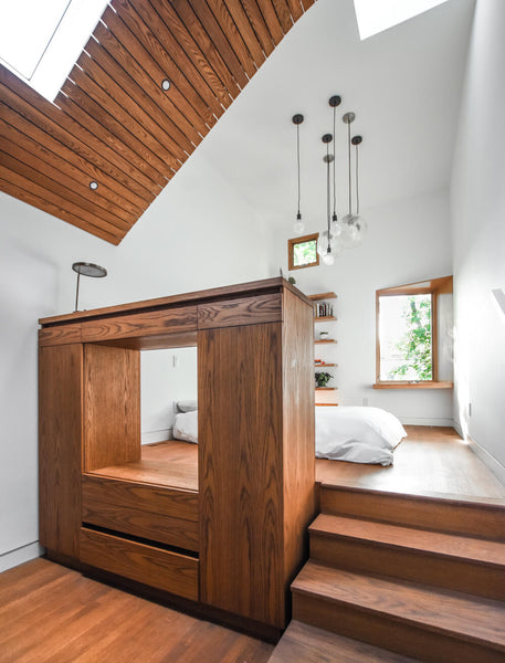 A bedroom made predominately from wood to include the bed platform, cabinetry and flooring. 