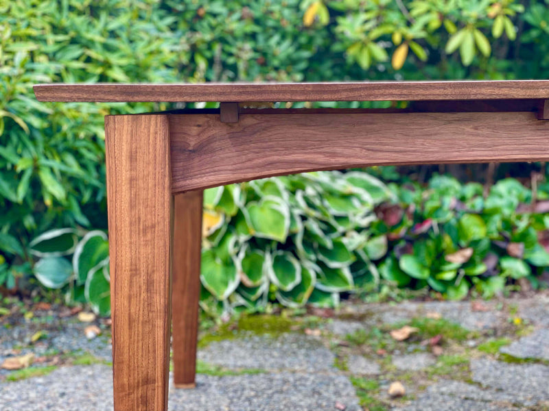 A walnut dining table with a floating top that is finished with a wood oil finish.