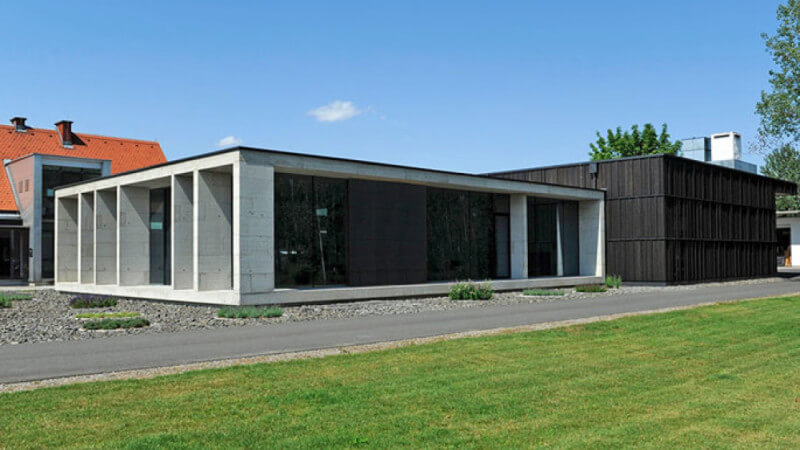 A view of a modern single-story home with wood panels and concrete.