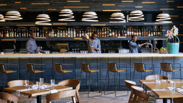 Three bartenders behind a cerused bar in a sushi restaurant.