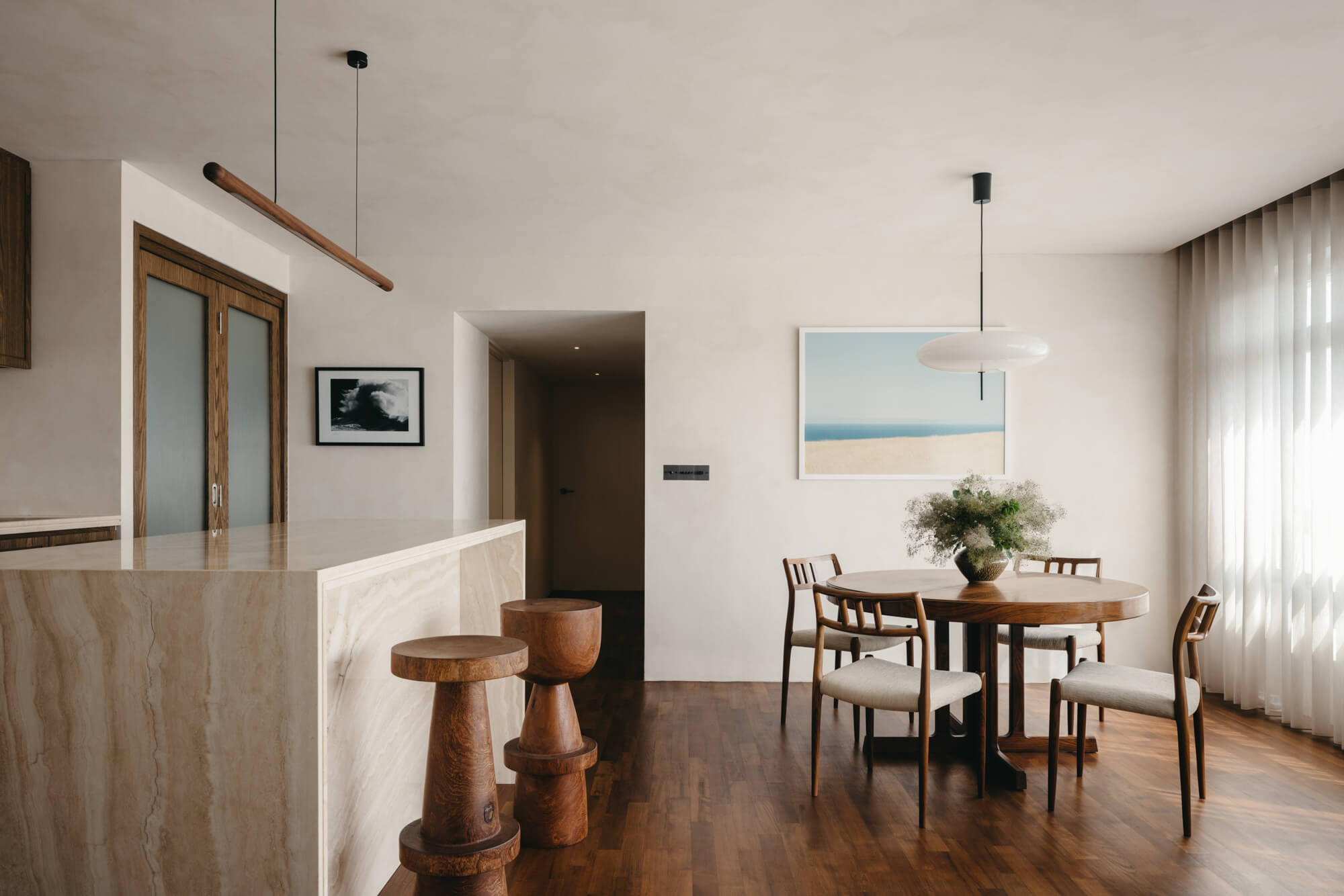 A stone waterfall island with two carved nightstands made from wood. Wood flooring also runs throughout this space. The wood elements are finished with Rubio Monocoat hardwax oil finish.