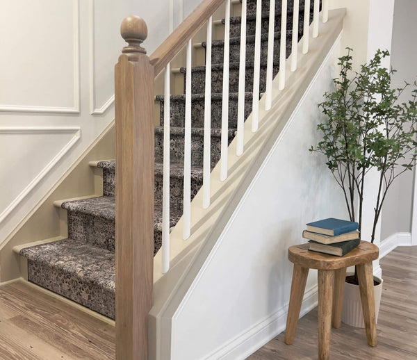 White oak stair railing complete with a stair post and rounded finial. Also pictured is a small vintage stool and potted tree.