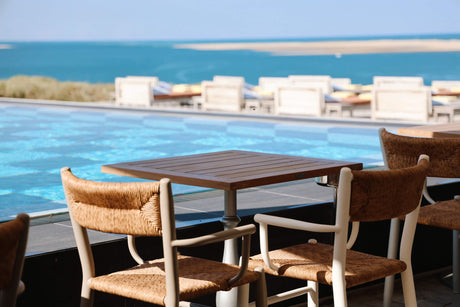 Outdoor wood dining table and chairs finished with DuroGrit beside a swimming pool