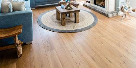 Chic living room with white oak wood flooring, a fireplace, couches, and coffee table on a rug.