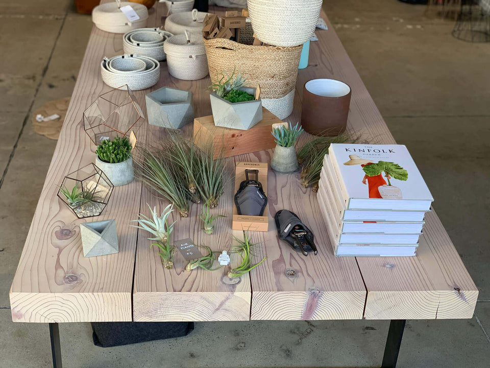 A thick redwood display table with a variety of retail items placed on it finished with Rubio Monocoat Oil Plus 2C hardwax oil.