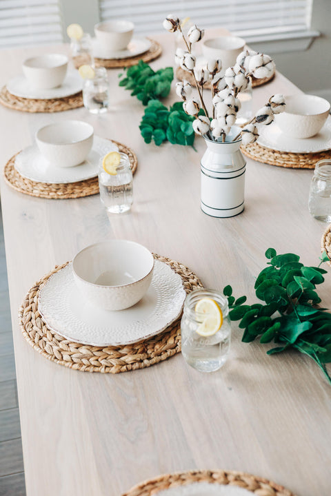 A white oak table set with several place settings.