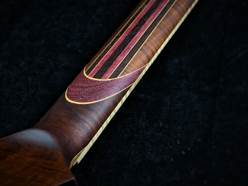 A photo of the back of the neck of the guitar shows the stunning variety of wood species used.