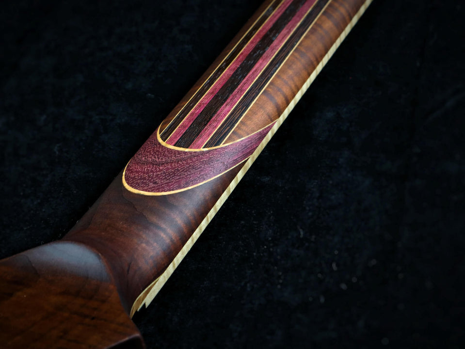 A photo of the back of the neck of the guitar shows the stunning variety of wood species used.