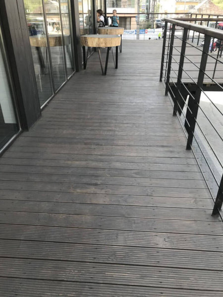 Wood patio at a restaurant with cable railing and wood tables.