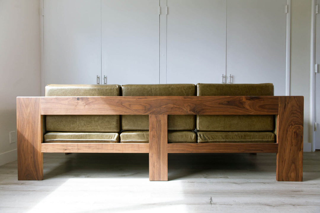 Back view of a custom sofa, with walnut wood base and olive green leather cushions.