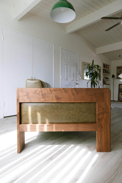 Side view of a handcrafted sofa made from walnut wood and leather.