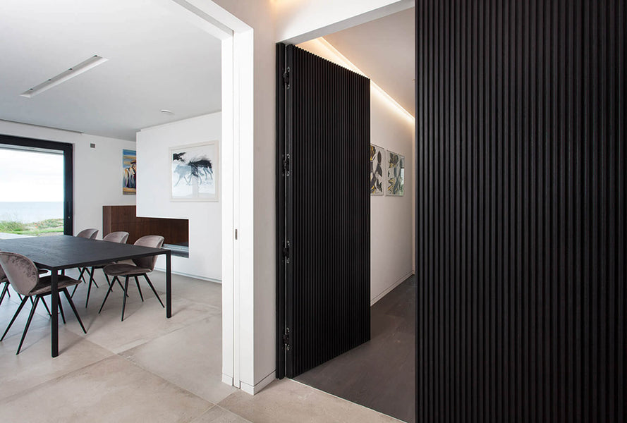 The hidden door hidden within the black slat wall. The door is open and you also see a dining set.