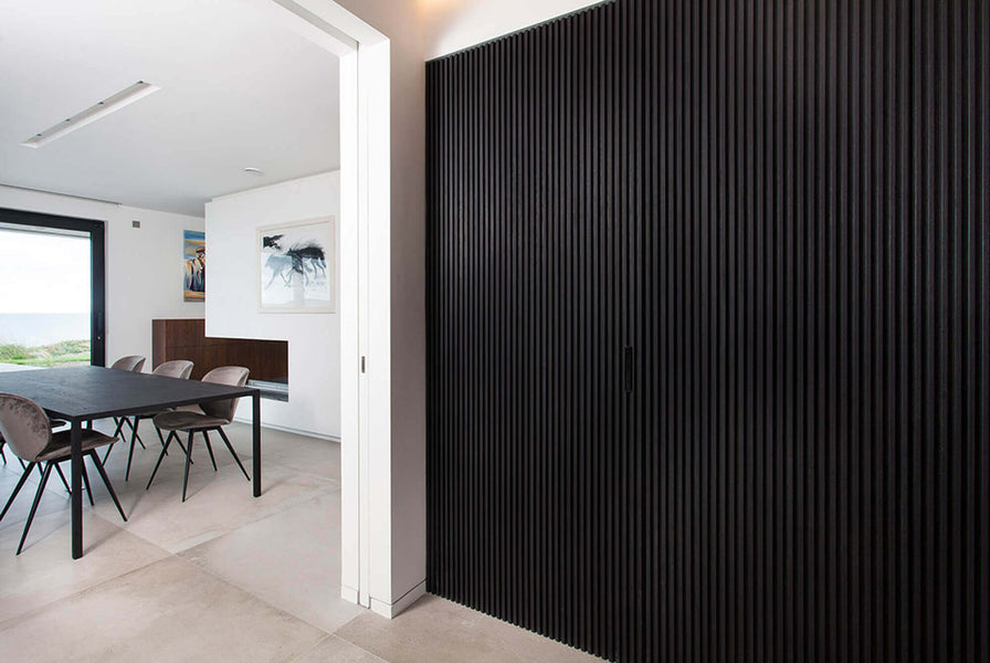 A view of where a hidden door exists in a black slatted wall.