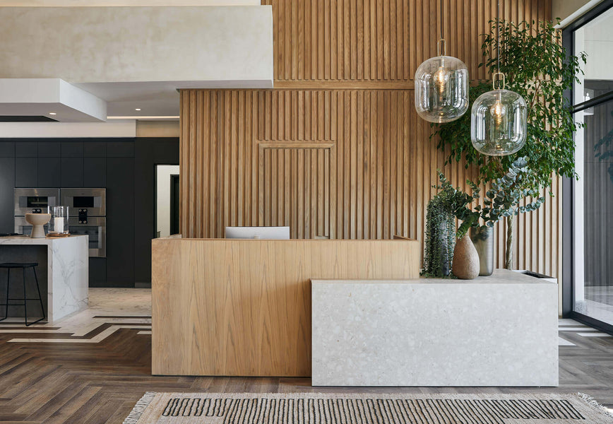 A light wood reception desk made of white oak and finished with a hardwax oil. Featured behind the desk is a slatted wood wall.