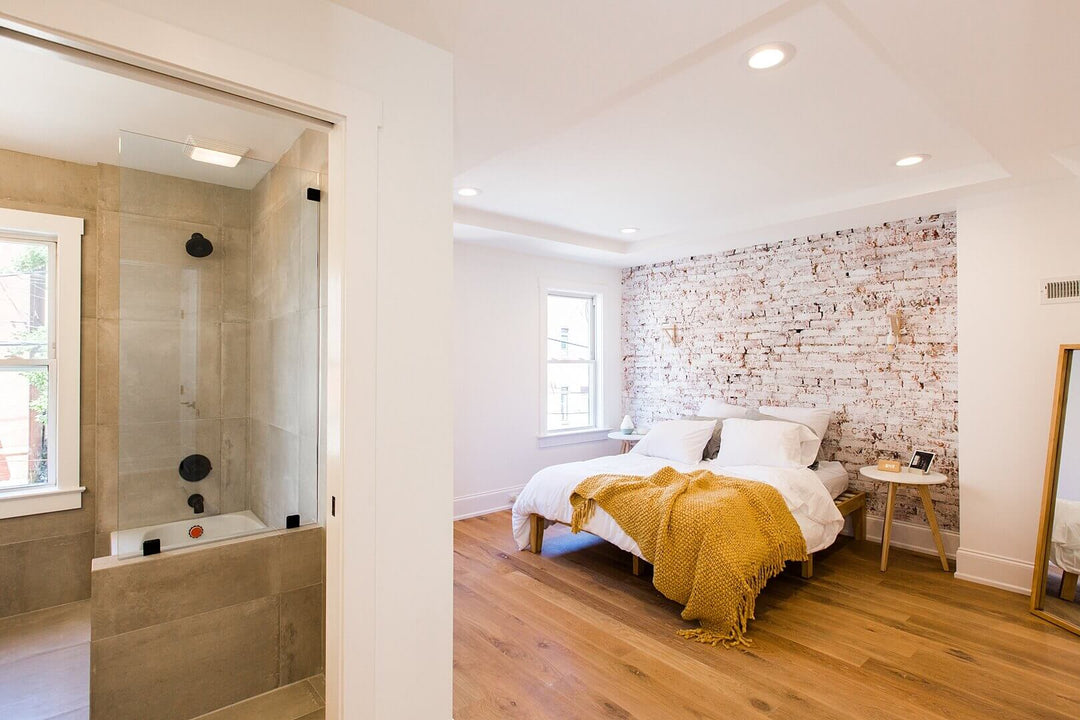 Master bedroom with hardwood flooring and a brick accent wall.