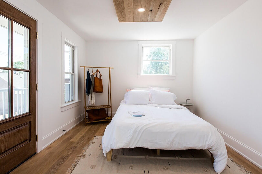 Bedroom with hardwood flooring and a white oak ceiling accent.