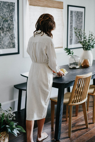 A woman places a bowl of fruit on a solid ash table finished with Rubio Monocoat products.