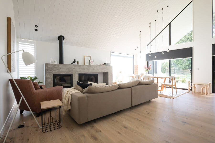 Open living room with tall ceiling, natural hardwood flooring, fireplace, and seating area.