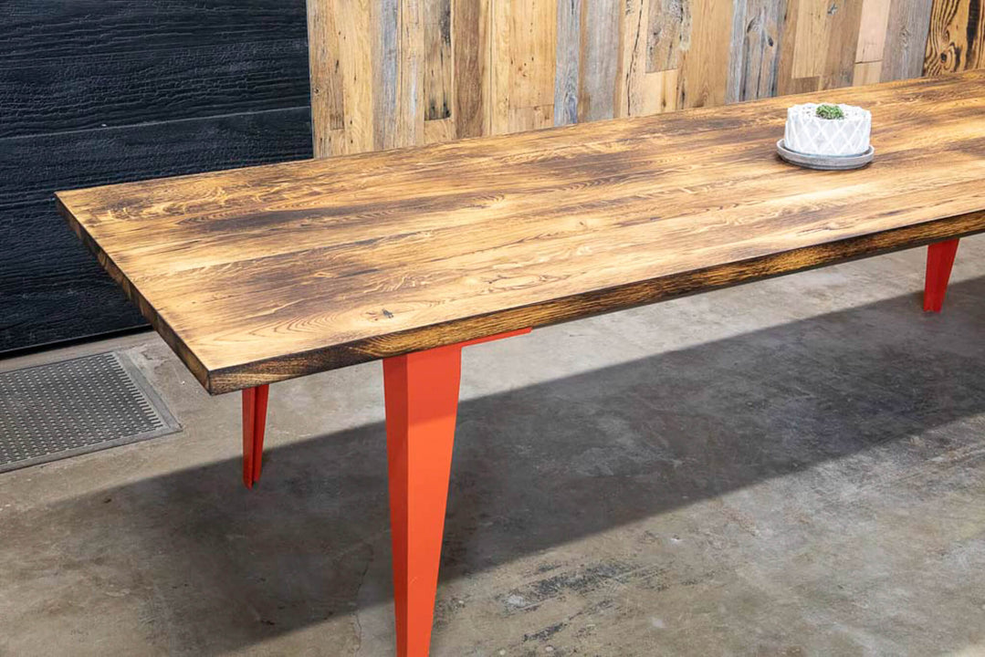White oak dining table with orange metal legs.