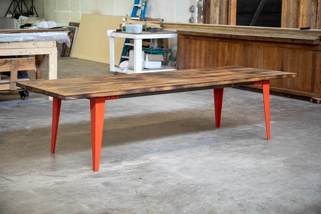 Charred white oak dining table with orange legs.