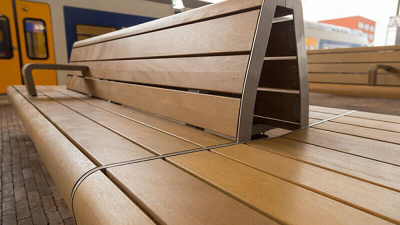 Details of a beautiful wooden bench at a train station.