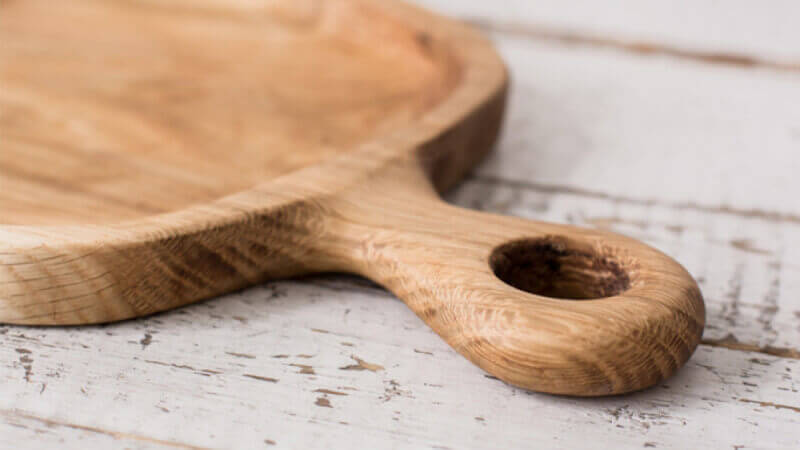 The handle of a wooden serving board that is finished with food safe wood finish.