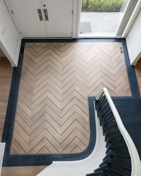 View from the balcony of custom chevron white oak floor featuring walnut accent strips and a dark cerused border.