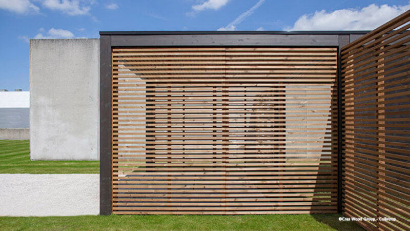 A carport with wood boards running lengthwise to create a barrier from the elements.