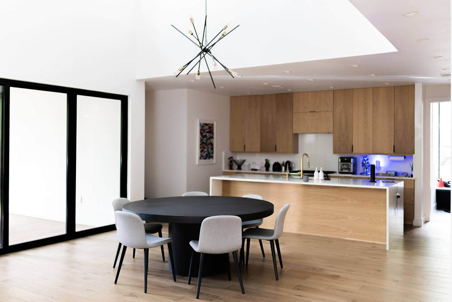 A wider angle view of the round dining table features a full view of the modern kitchen.