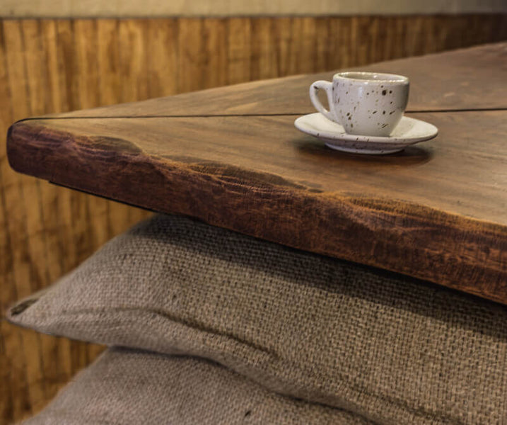Close up of wooden counter tops and a cappuccino cup sitting on the counter.