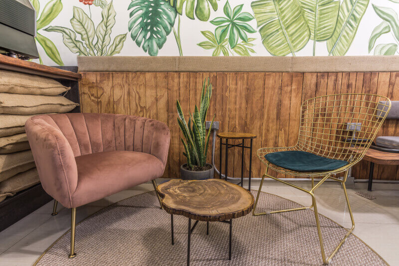 Different chairs and decor make up a cozy seating area inside a trendy coffee shop.