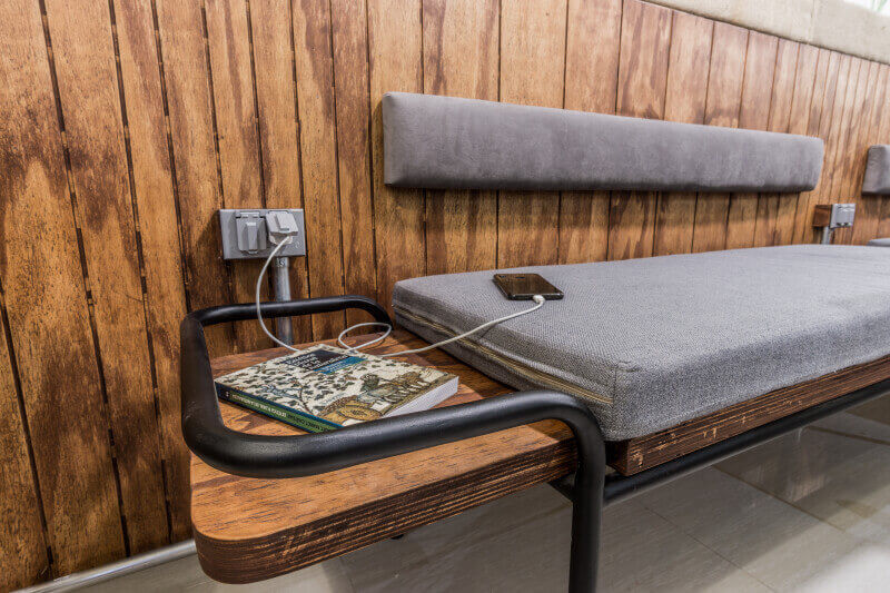 A custom cushioned bench made from wood and metal sitting against a wooden panel wall.