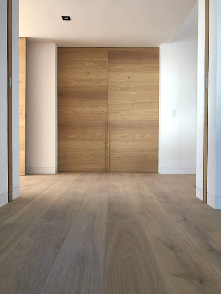 Wide plank oak flooring with white walls and natural color oak barn doors.