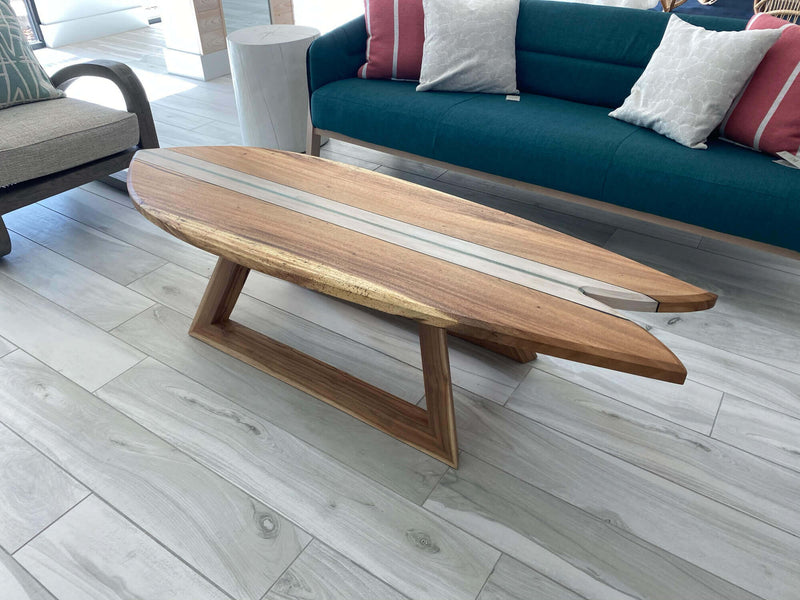 Wood surfboard shaped coffee table with a geometric base.