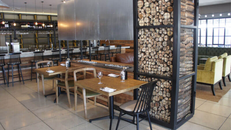 Rustic restaurant decor with wood logs inside a steel cage.