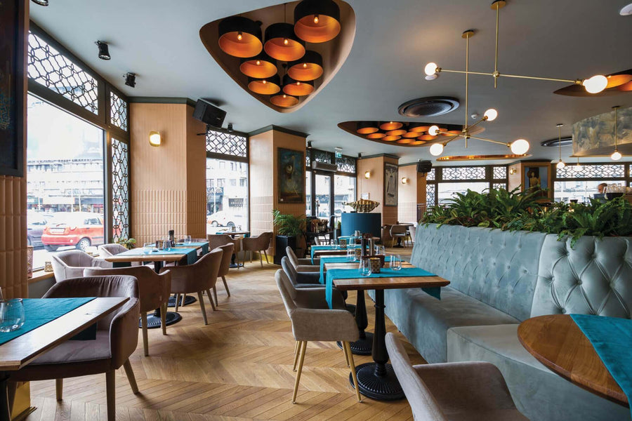 Restaurant with oak flooring in a chevron pattern, with bench seating and large decorative lights in the ceiling.