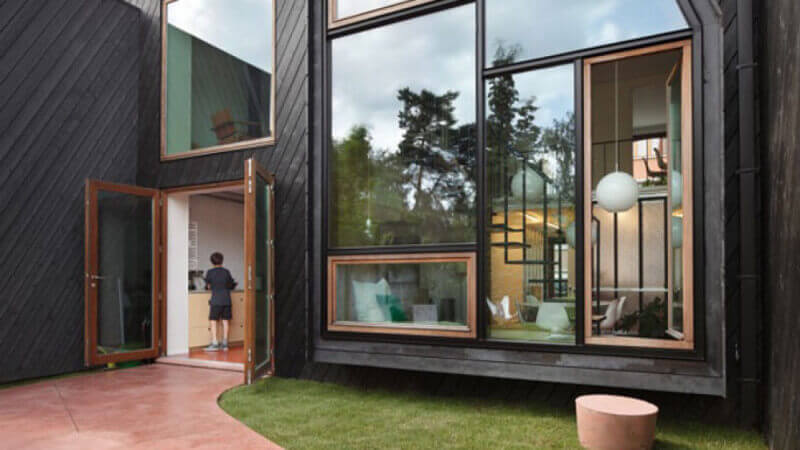 A boy walking into the wide open front french doors of a masterfully designed city home.