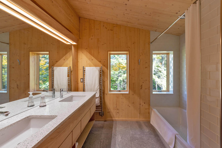 A contemporary bathroom with white stone countertops and wood paneling finishing with Rubio Monocoat Oil Plus 2C.